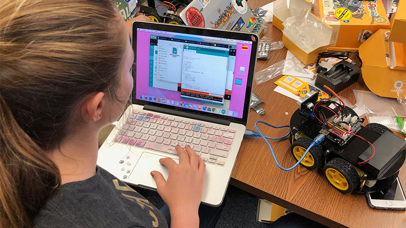 Student programming a robot using a laptop