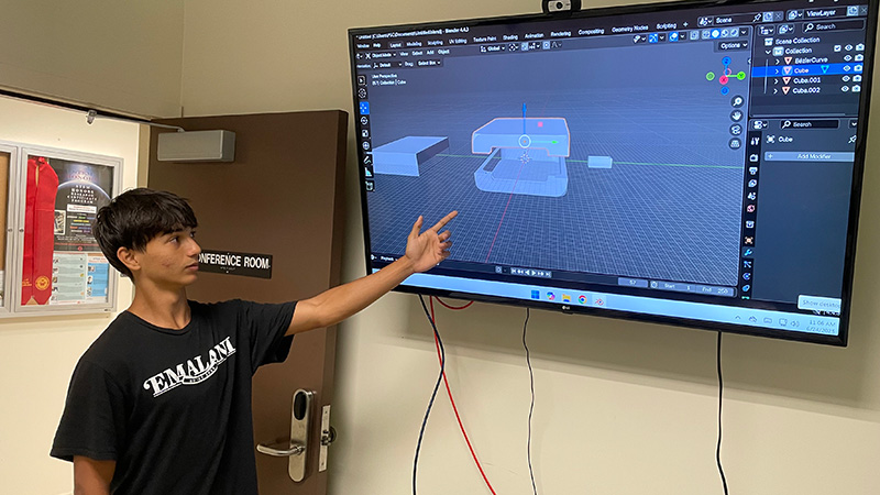 Intern Cory Aukai shows his CAD design model on a large monitor.