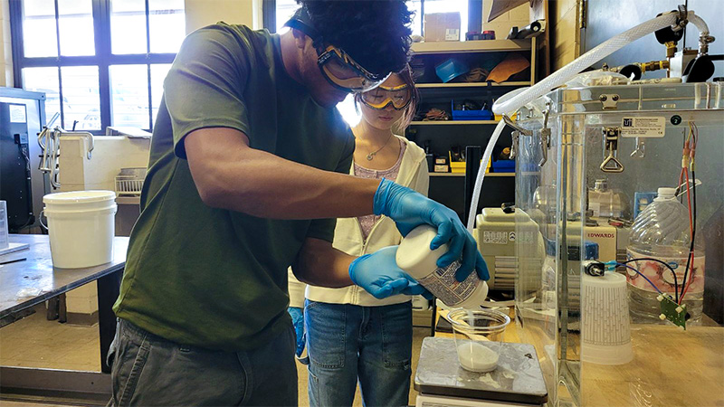 Interns mix geopolymer concrete using Hawaiian basalt.