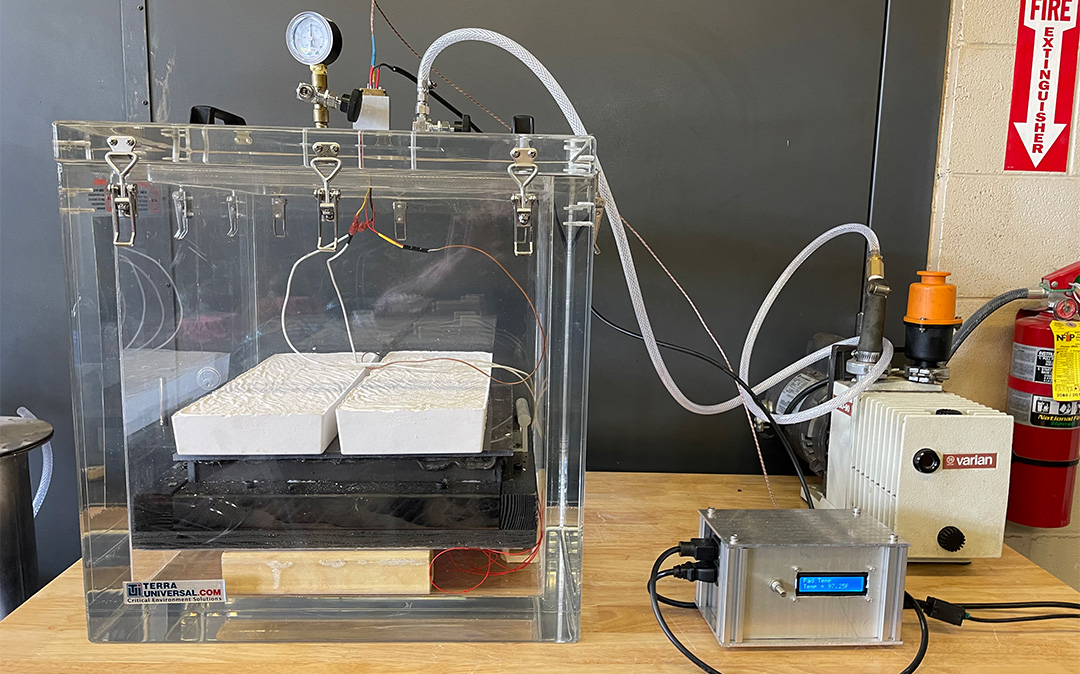 Vacuum chamber with binder-regolith composite curing inside.