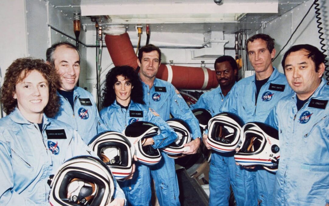 The seven members of the Space Shuttle Challenger crew pose together in their flight suits.