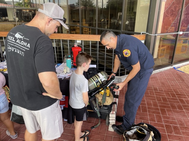 First responder demonstrates paramedic gear to a student at Onizuka Day.